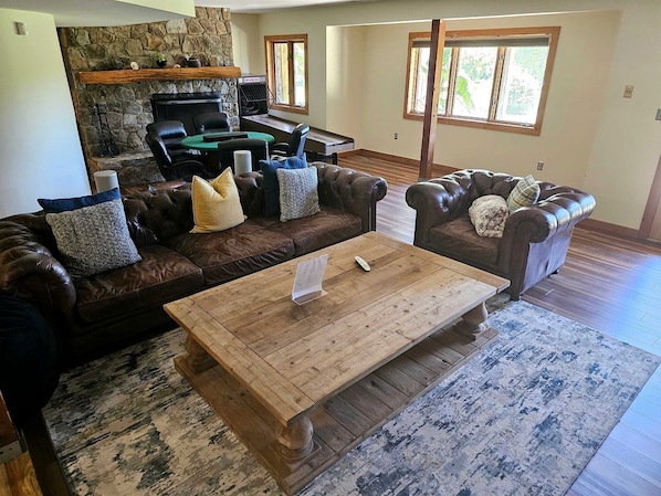 A living room with a fireplace, leather sofas, a coffee table, and a large rug.
