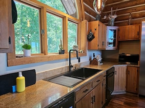 A kitchen with wooden cabinets, a stainless steel sink, and a dishwasher.