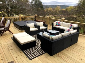 Una terraza con mobiliario exterior, incluyendo sofás y una mesa de centro, y vistas del paisaje circundante.