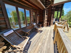 A wooden deck with lounge chairs and a wooden railing.