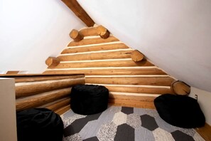 A sloped ceiling with wooden beams, a geometric patterned rug, and two black bean bags.