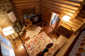 A log cabin interior with a bed, a desk, and a chair.