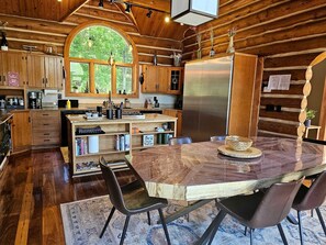 Una cocina rústica con armarios de madera, una isla grande con encimera de mármol y un refrigerador de acero inoxidable.