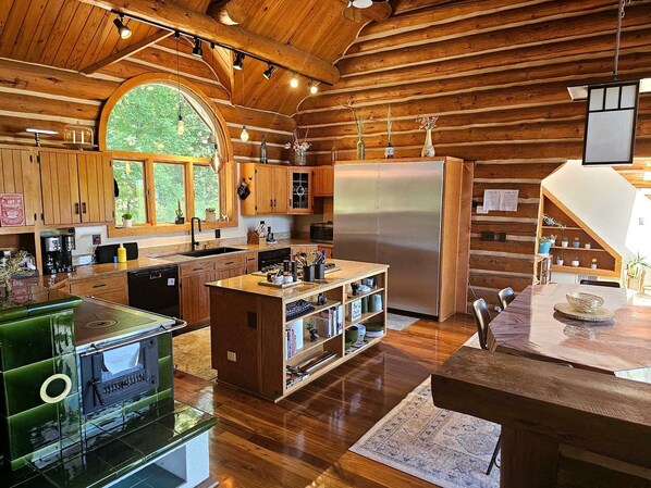 A spacious kitchen with wooden beams, a large island, and a built-in oven.