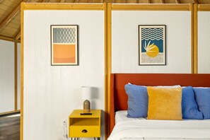 A room with a bed, a nightstand, a lamp, and two framed artworks on the wall. - Luxurious Connected Yurt Cabins with Private Hot Tubs Near Canyon Lake, Texas Hill Country (Canyon Lake)