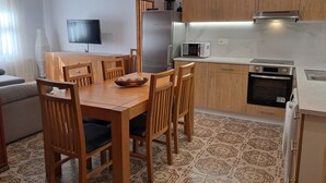 Una cucina moderna con mobili in legno, un tavolo da pranzo con sedie, un frigorifero, un forno a microonde e un forno.