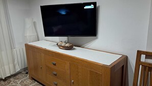 Un televisore montato a parete sopra un mobiletto contenitore con cassetti.