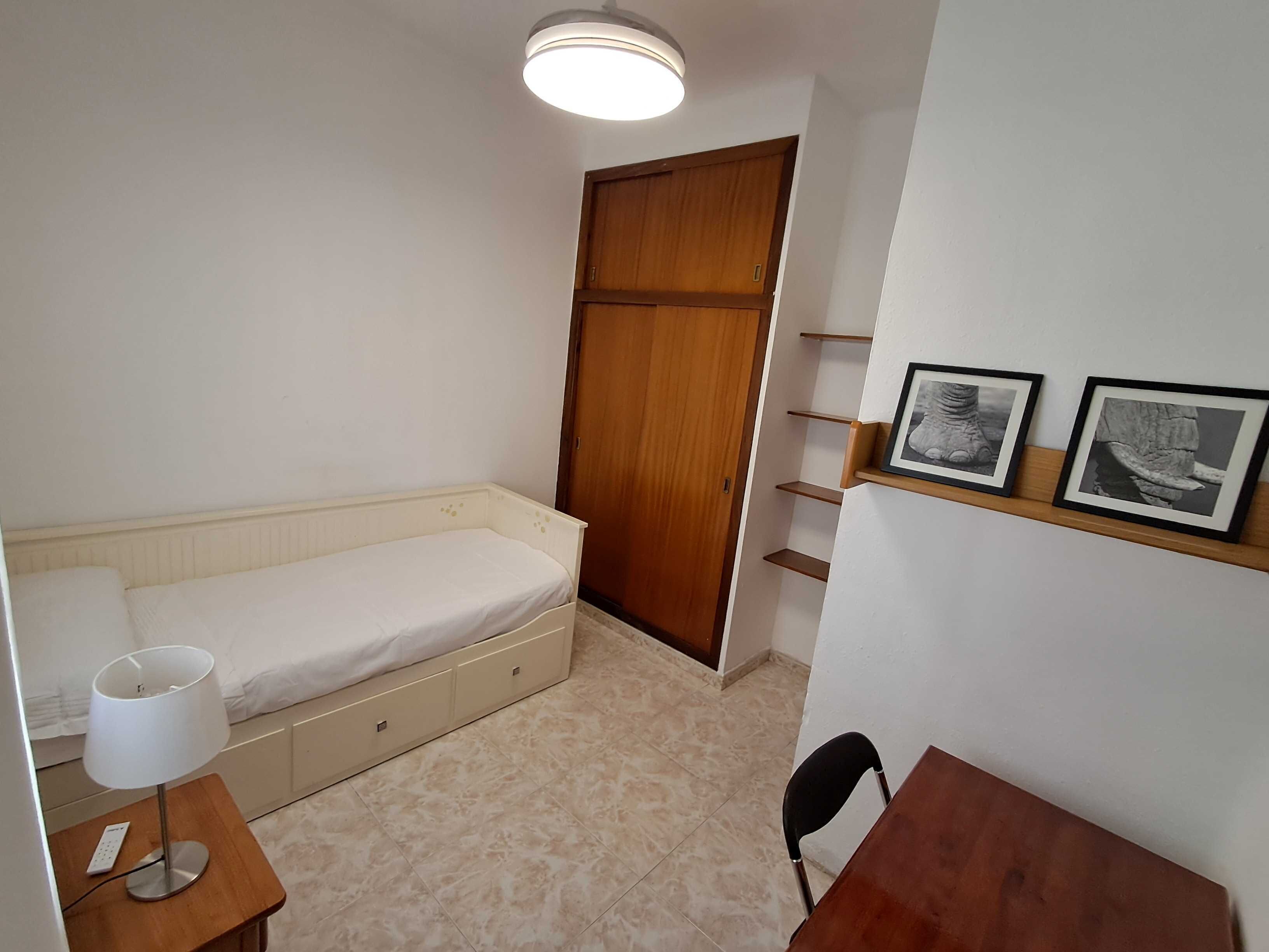 Ein Schlafzimmer mit Bett, Nachttisch, Lampe und einem Holzschrank.