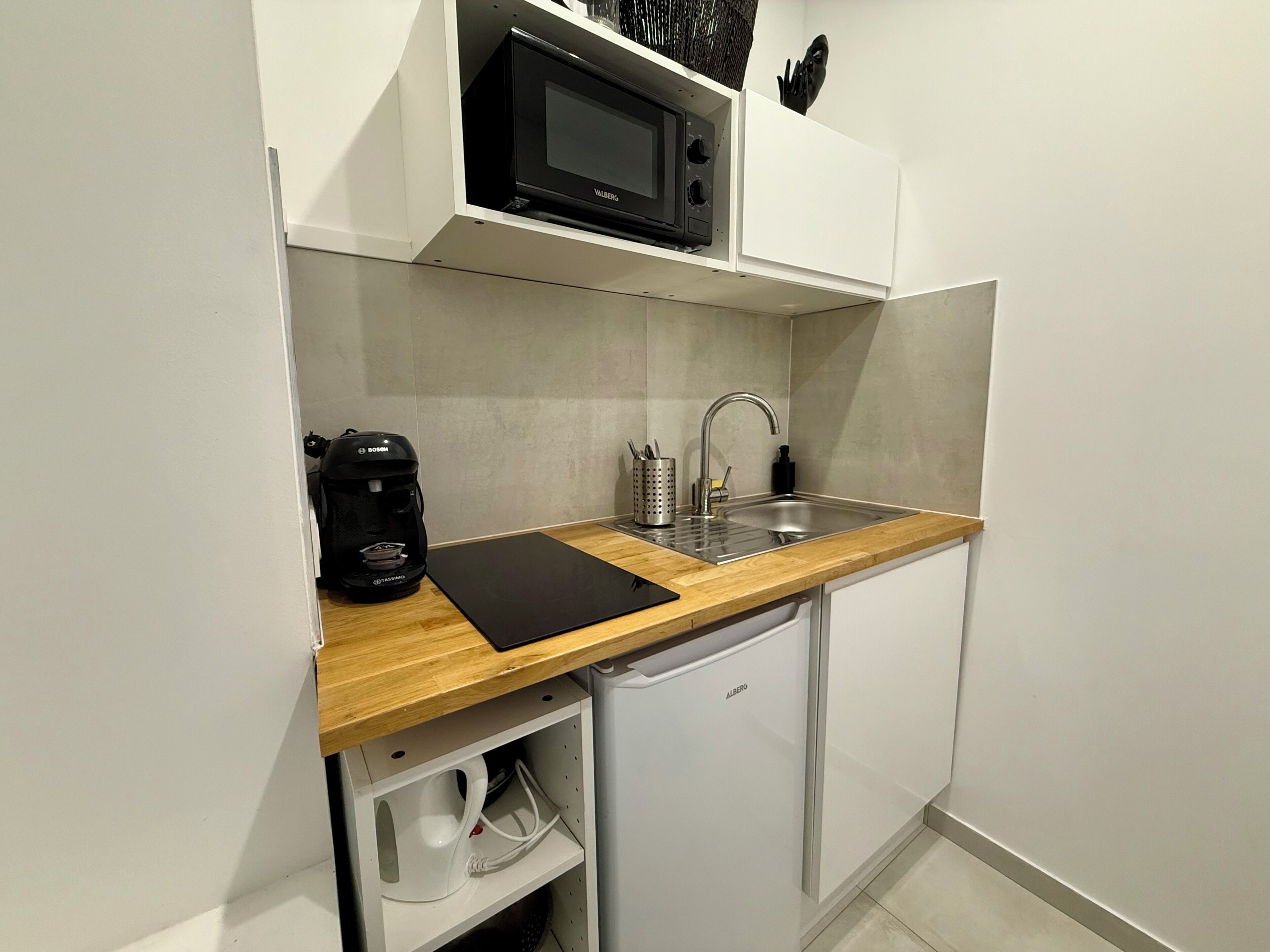 A compact kitchen with a microwave, coffee maker, sink, and a dishwasher.