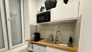 Een kleine keuken met een magnetron, koffiezetapparaat, spoelbak en vaatwasser.
