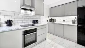 A modern kitchen with white cabinetry, a built-in oven, a microwave, and a kettle. - Sleeps5-freeparking-familyfriendly-5mintostation (London)