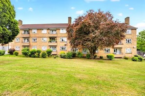 A multi-story residential building with a flat roof, multiple windows, and a well-maintained lawn in front. - Sleeps5-freeparking-familyfriendly-5mintostation (London)