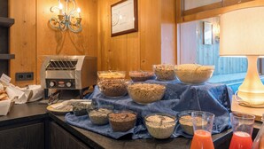 A buffet setup with various food items and a toaster oven. - Hotel Alpenflora (Castelrotto)