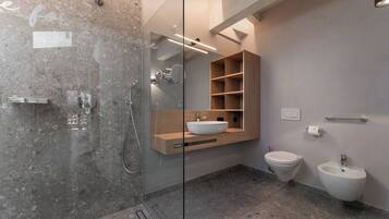 Ein modernes Badezimmer mit einer gläsernen Duschkabine, einem hölzernen Waschtisch mit Aufsatzbecken, einer Toilette und einem Bidet.