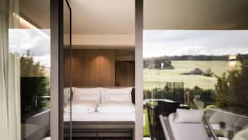 Un dormitorio moderno con una cama grande, paneles de madera y un balcón con mobiliario exterior.