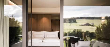 A modern bedroom with a large bed, wooden paneling, and a balcony with outdoor furniture.