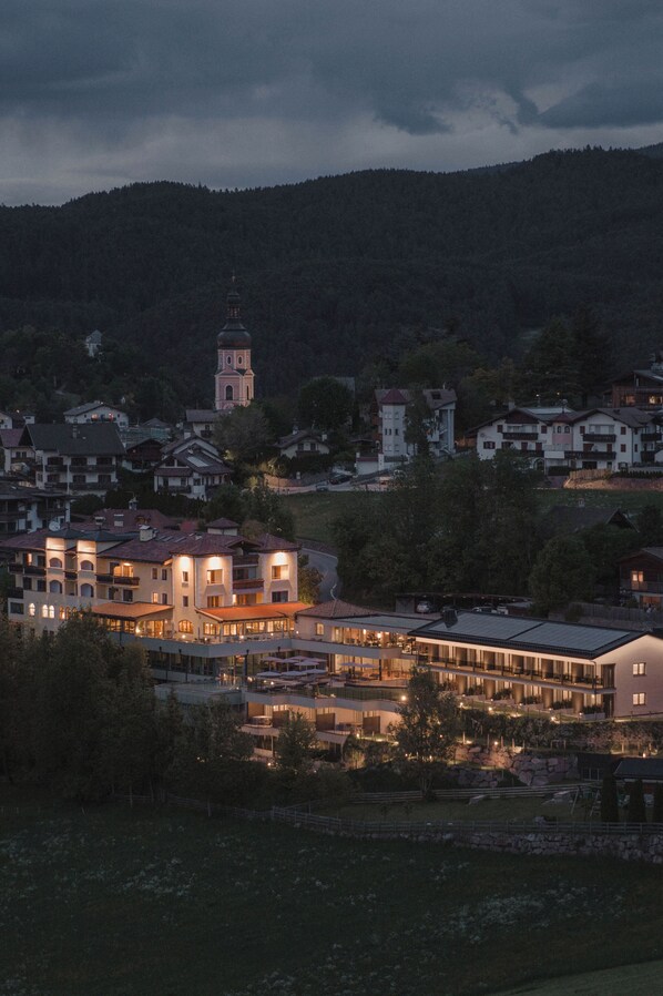 A town with a prominent church tower, a modern hotel with multiple floors, and surrounding residential buildings.
