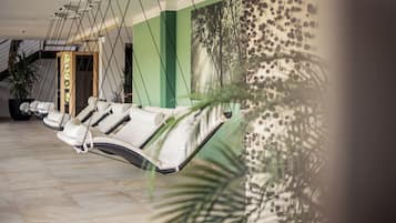 A spa area with reclining chairs, a green wall, and a large plant.
