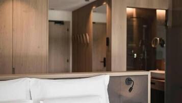 Habitación de hotel con una cama grande, una mesita de noche con lámpara y paneles de madera en las paredes.