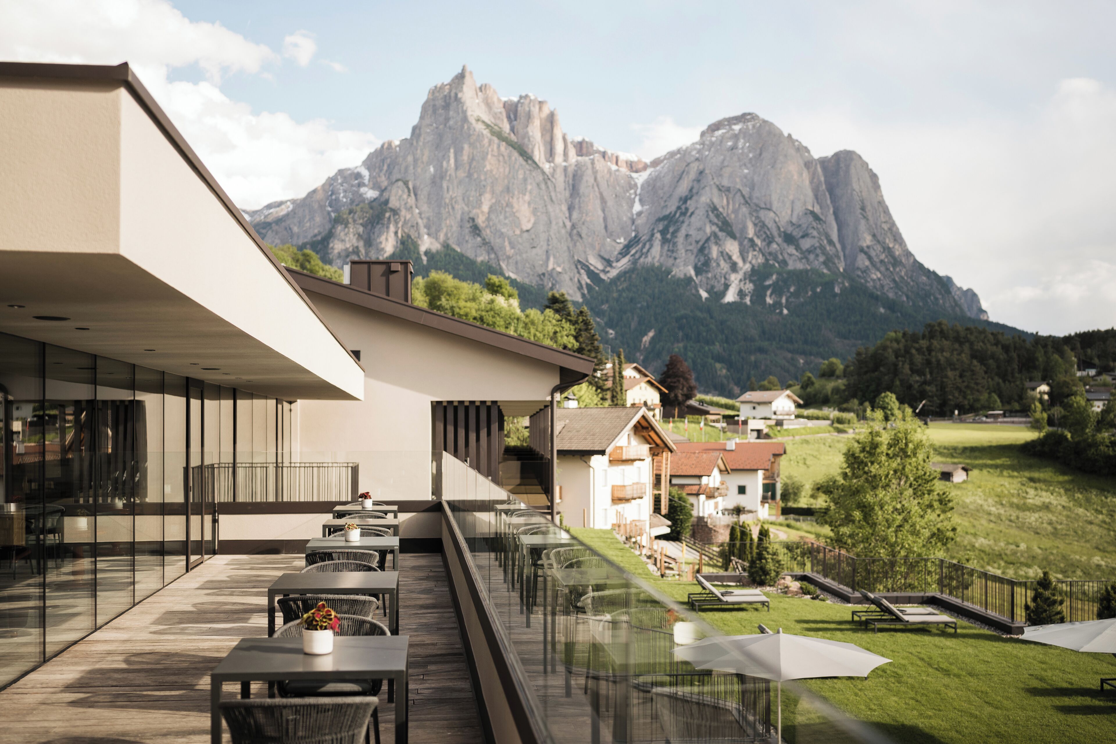 Un espacio al aire libre moderno con mesas y sillas, con vistas a un paisaje montañoso.