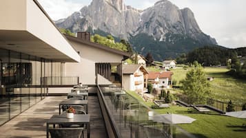 Un espacio al aire libre moderno con mesas y sillas, con vistas a un paisaje montañoso.