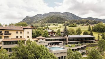A hotel with multiple buildings, a swimming pool, and a mountainous backdrop.