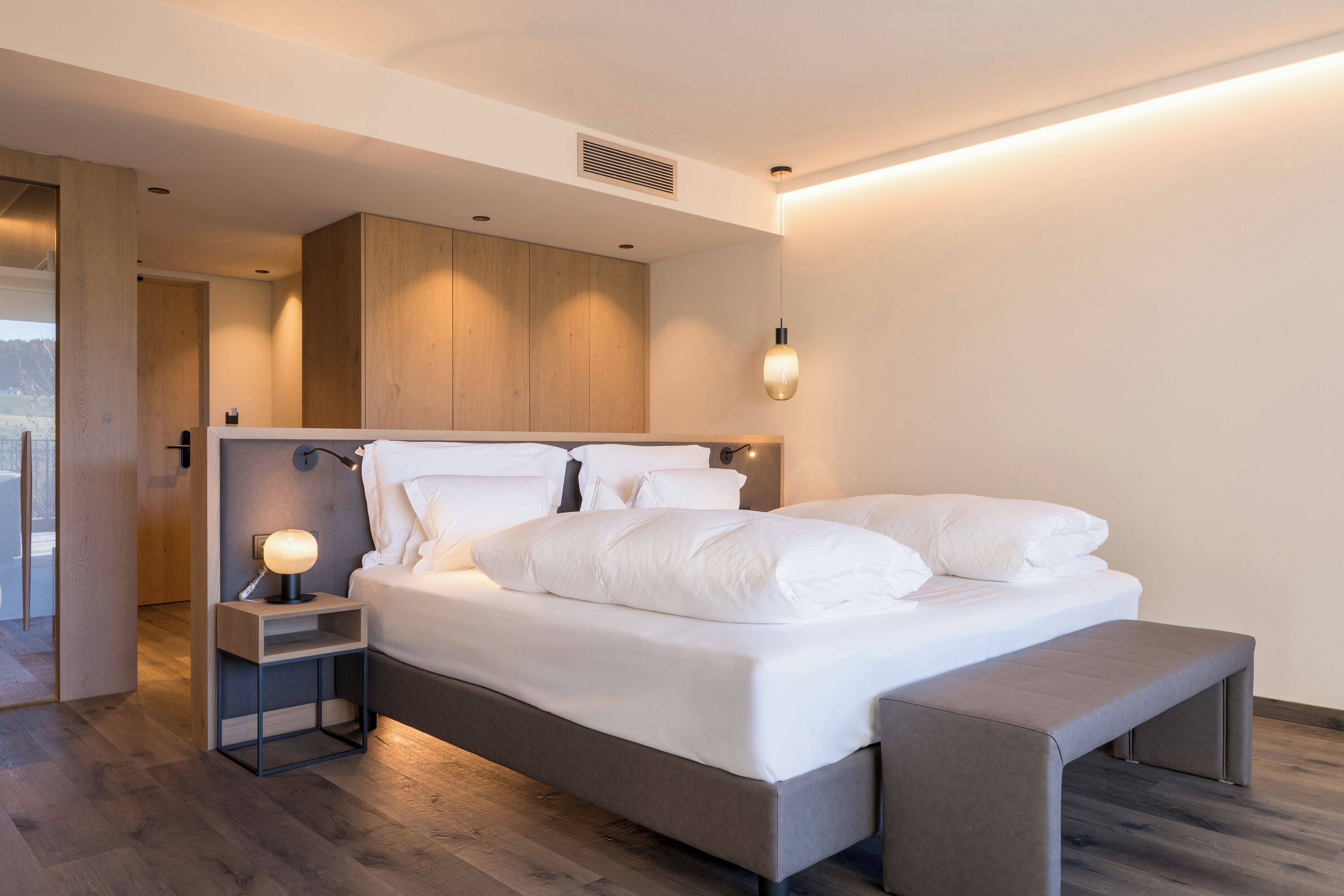 Un dormitorio moderno con una cama grande, mesitas de noche y un banco.