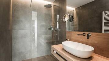 Ein modernes Badezimmer mit einem großen Spiegel, einem Holzwaschtisch und einer gläsernen Dusche.