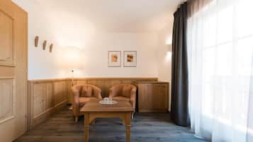 A room with a wooden bench, a table, and a lamp. There are two framed pictures on the wall.