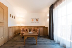 A room with a wooden bench, a table, and a lamp. There are two framed pictures on the wall.