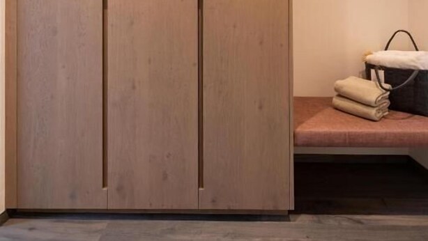 A room with a wooden wardrobe, a bench, and a wall-mounted coat rack. - Hotel Alpenflora (Castelrotto)