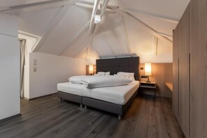 Un dormitorio con cama, lámparas de noche y un armario de madera.