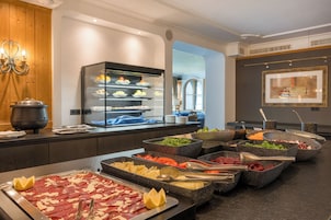 Ein reichhaltiges Buffet mit verschiedenen Speisen, darunter Fleisch, Gemüse und Obst.