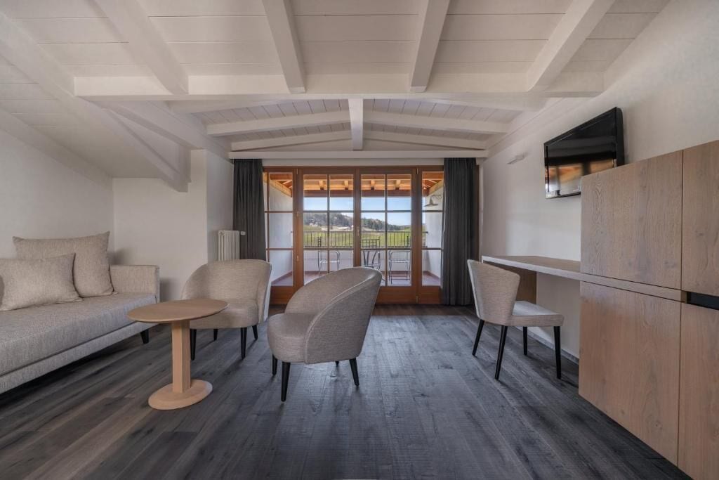 Un intérieur moderne avec un canapé, des fauteuils, une petite table et un téléviseur fixé au mur.