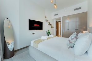Ein modernes Hotelzimmer mit einem großen Bett, einem Flachbildfernseher, einem Spiegel und einem Kleiderschrank.