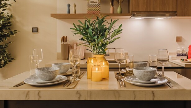 A dining table set with plates, bowls, glasses, and candles, with a potted plant in the center. - PVH - Urban Oasis by Missoni - 1BR (Dubai)