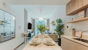 A modern kitchen with a marble countertop, a dining table set for six, and a view into the living area. - PVH - Urban Oasis by Missoni - 1BR (Dubai)