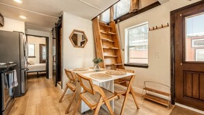 A kitchen with a wooden table, chairs, a refrigerator, and a ladder. - Beautiful Tiny Home Nestled in Woodland Park and near Manitou Springs, Perfect for a Weekend Getaway (Woodland Park)