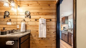 A wooden-paneled bathroom with a sink, mirror, towel rack, and hanging towels. - Beautiful Tiny Home Nestled in Woodland Park and near Manitou Springs, Perfect for a Weekend Getaway (Woodland Park)