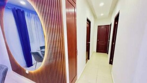 Un pasillo con un elemento decorativo en forma de arco, una puerta y una silla.