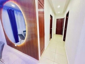 A hallway with a curved wall feature, a door, and a chair. - Premium Apartment in the East Side (Santo Domingo)