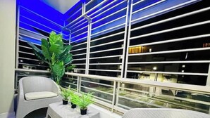 Un balcón con una silla de mimbre, una mesita y plantas en macetas.