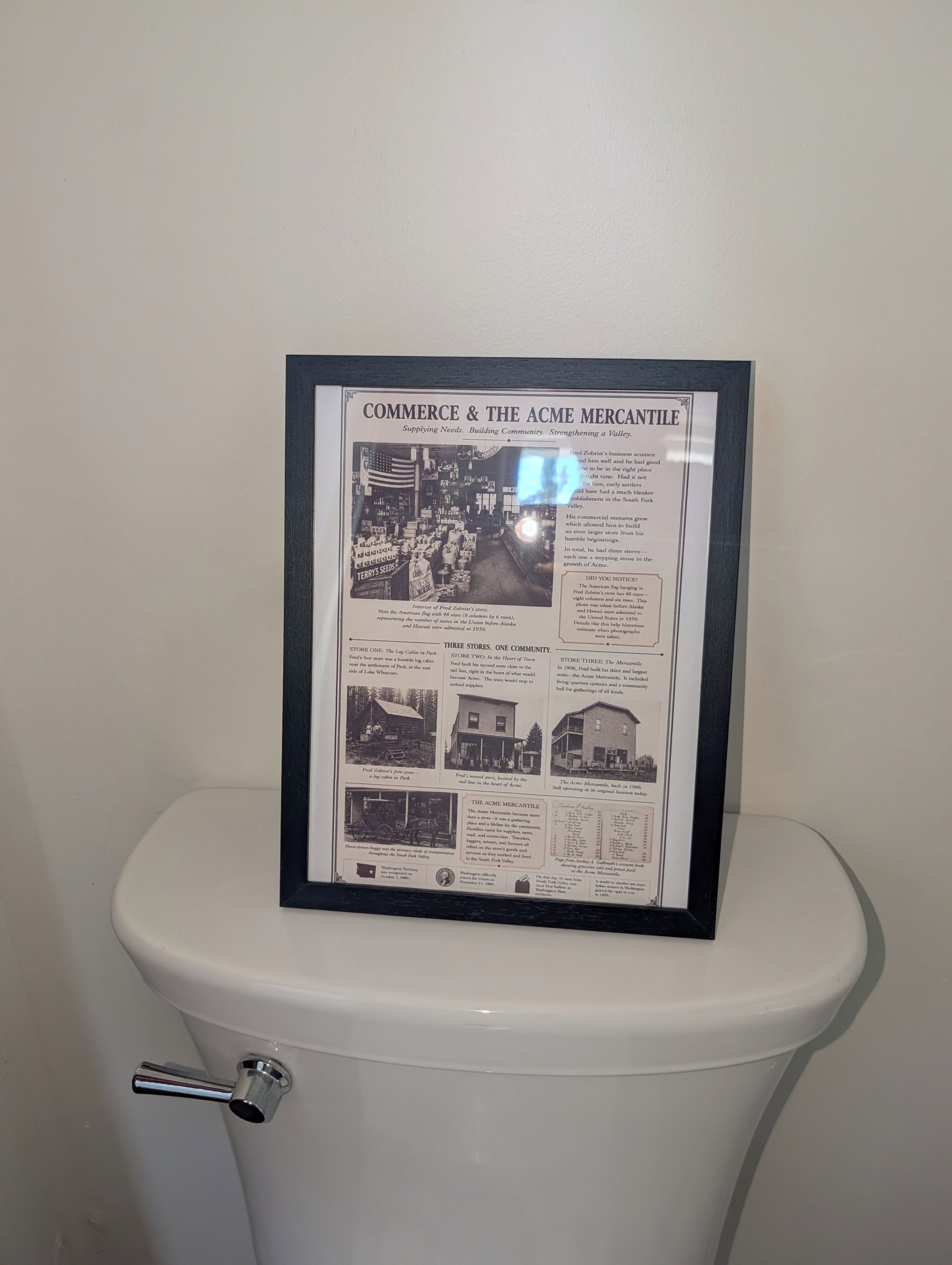 Ein gerahmtes historisches Dokument mit der Aufschrift 'COMMERCE & THE ACME MERCANTILE' auf einem Toilettendeckel.