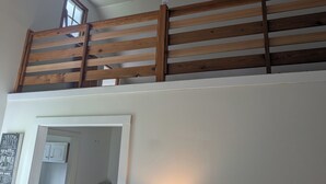Une pièce avec un plafond en pente, une balustrade en bois et un mur blanc orné d’une citation encadrée.