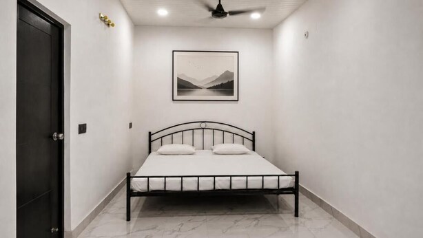 A bedroom with a bed, a ceiling fan, a framed picture on the wall, and a door.