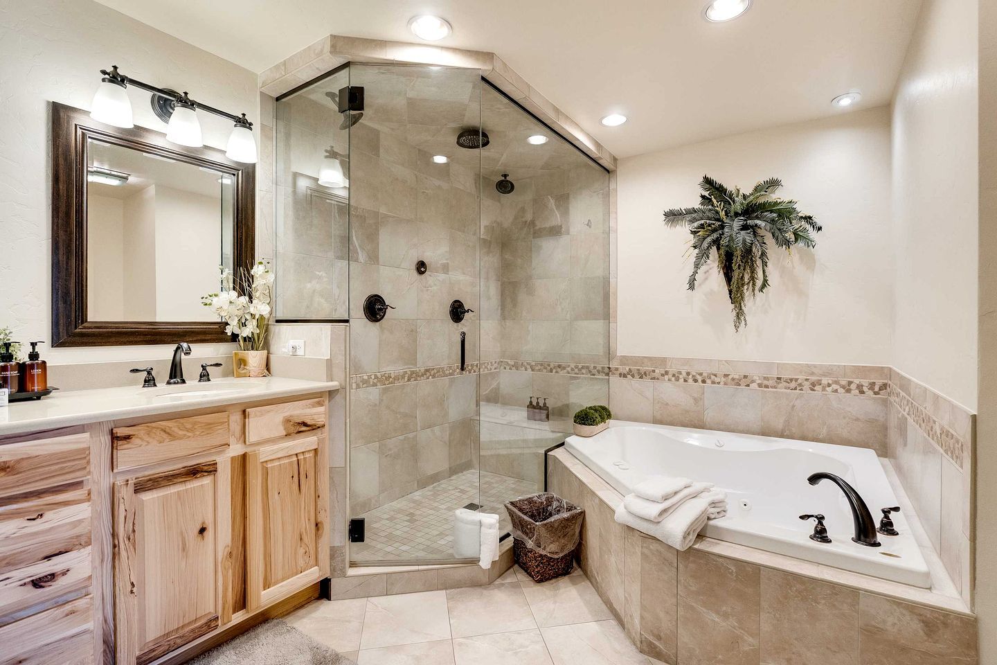 Un baño moderno con ducha envuelta en vidrio, una bañera independiente y un mueble de tocador de madera.