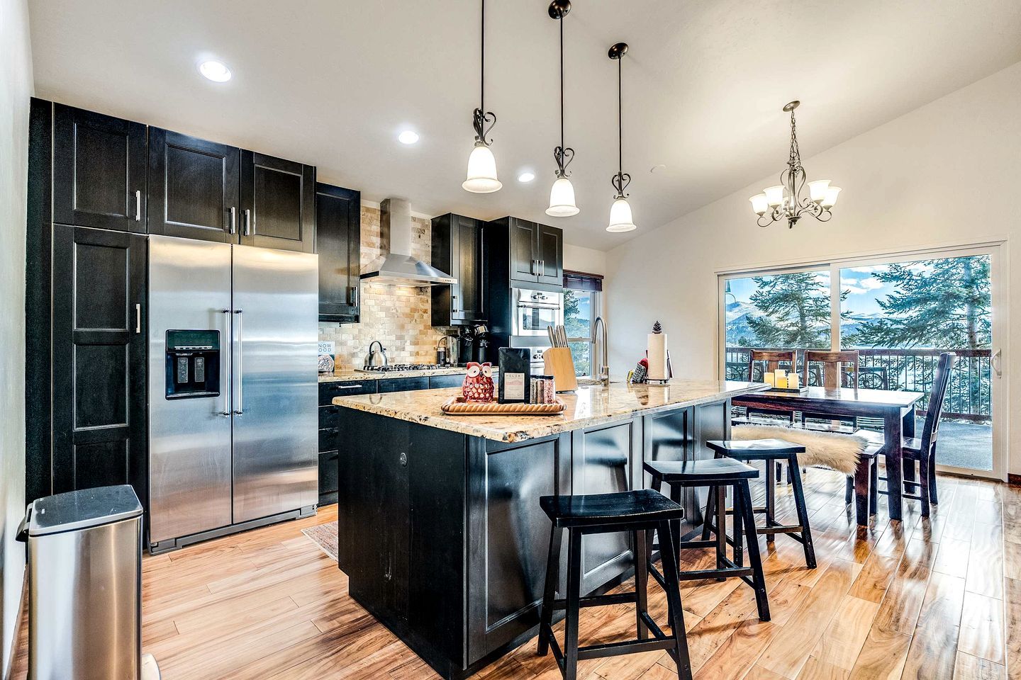 A modern kitchen with a large island, stainless steel appliances, and a view of the outdoors.