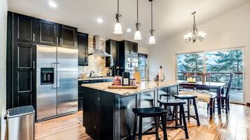 A modern kitchen with a large island, stainless steel appliances, and a view of the outdoors.