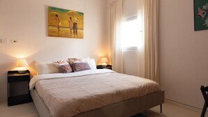 Ein Hotelzimmer mit Bett, zwei Nachttischlampen, einem Bild an der Wand und einem Vorhangfenster.