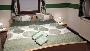 A bedroom with a bed, curtains, a window, and bedside lamps. - Ulbersdorf Mill "Försterstübchen" (Hohnstein)